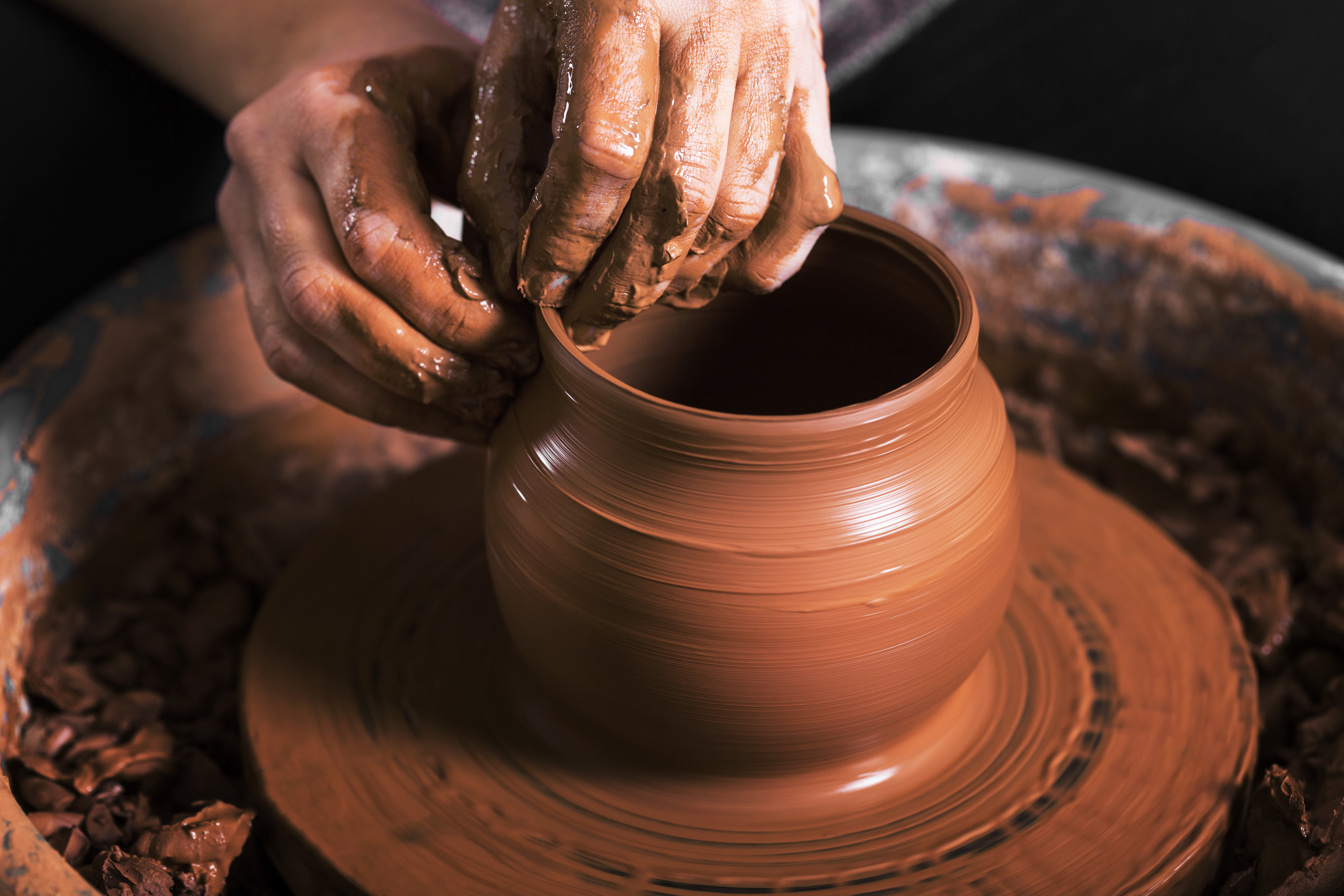 Hands shaping a vessel on a potter's wheel — the final form emerging from raw clay