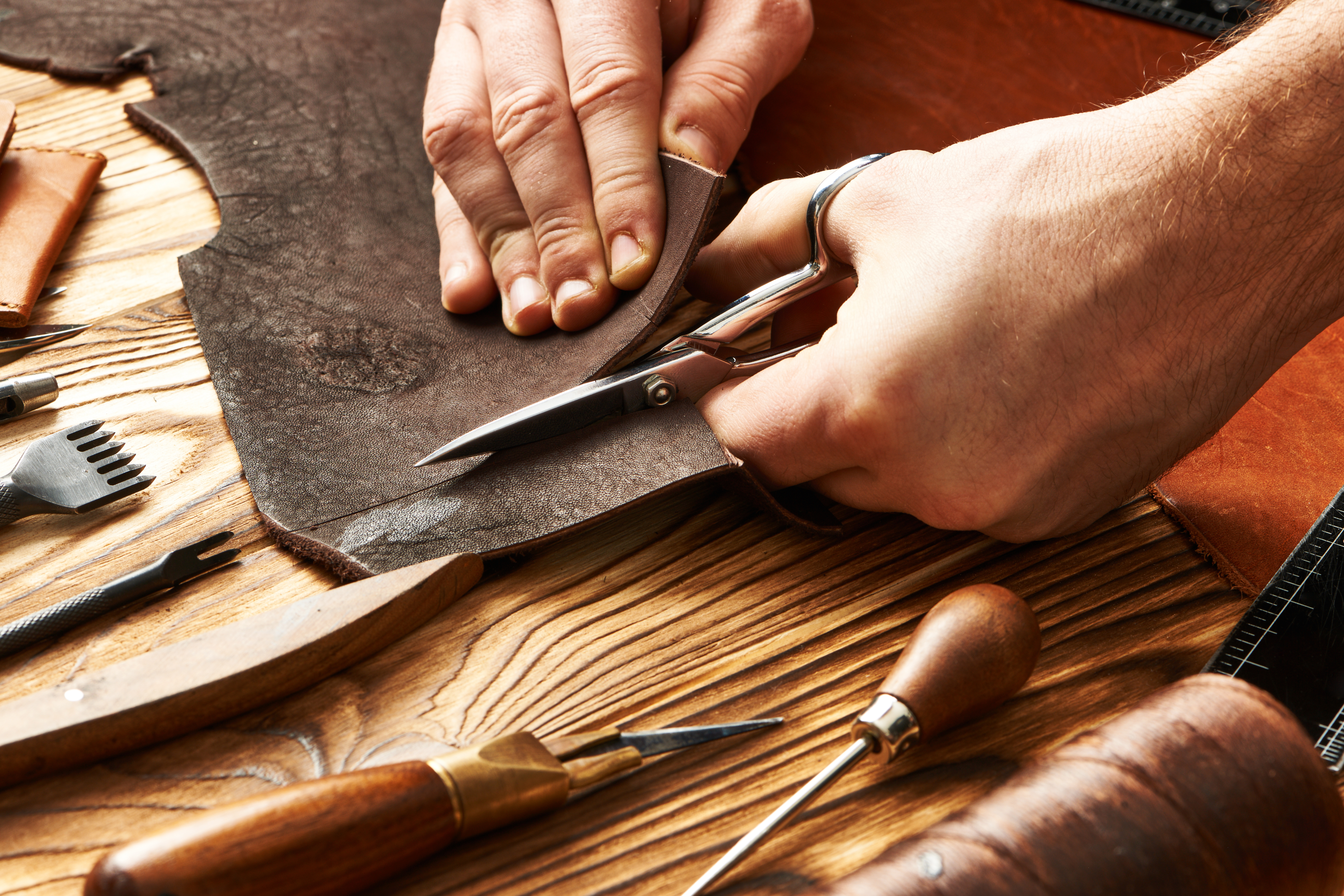 Leatherworker cutting material with precision tools — craft visible in every choice